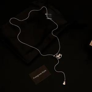 Detail of silver snake chain with crystal horse pendant and dollar sign charm