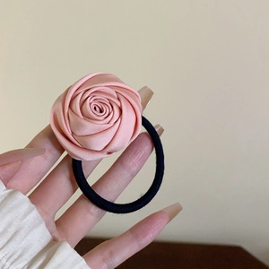 Détail d'un chouchou rose en satin en forme de rose avec un élastique noir durable
