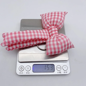 Pink checkered bow pendant shown on an electronic scale weighing 15.3g for accuracy