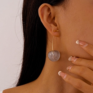 Detailed close-up of cherry-shaped acrylic earrings with glitter spheres and gold studs