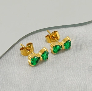 Detail view of 18K gold bow earrings with green zircon stones at a 45-degree angle
