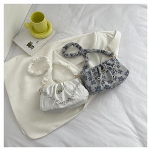 Detail of floral texture shoulder bags with stylish metal flower chains on white fabric