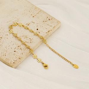 Elegant gold stainless steel flower bracelet with blue center petals on stone surface