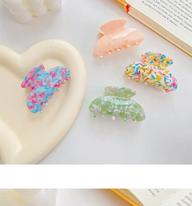 Detail of four colorful acetate hair claws in various patterns on a heart-shaped plate