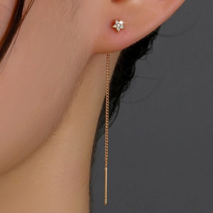 Close-up of gold star long tassel earrings with sparkling zircon on ear model