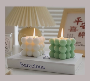Close-up of lit bubble cube candles in white and green on a book with warm ambient lighting