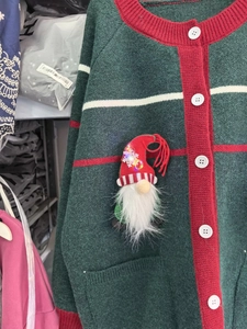 Detail of green knitted cardigan with red stripes and LED gnome brooch accessory