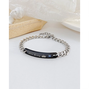 Macro view of silver steel bracelet with black pendant featuring Her King engraving