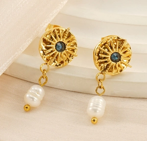 Detail of vintage sunburst earrings with blue gemstone and white baroque pearl charm