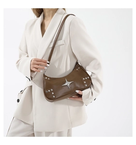 Detail of a brown leather shoulder bag with silver rivets and metal star ornaments