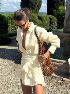 Detail of light yellow shirt dress featuring lapel collar and waist tie with ruffled hem