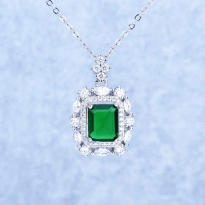 Close-up of emerald green princess cut pendant with micro-pave diamond halo in silver