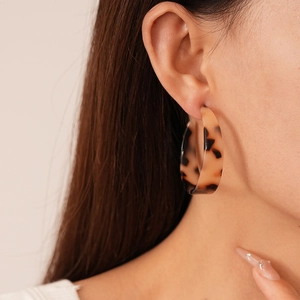 Vue latérale d'une femme portant des boucles d'oreilles créoles C en résine léopard