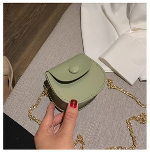 Détail du mini sac selle vert sauge avec chaîne dorée et cuir synthétique lisse