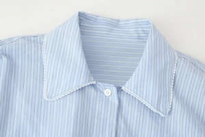 Detail of light blue striped shirt collar with white lace trim and round button