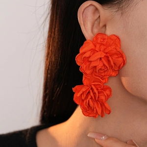 Vibrant orange fabric floral earrings featuring multilayered petals on female model
