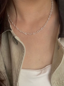 Macro detail of textured silver geometric link chain necklace on model collarbone