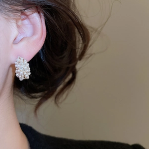 Close-up of a model wearing C-shaped pearl and zircon stud earrings in French retro style