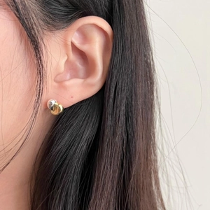 Minimalist silver and gold interlaced knot stud earrings shown in a side-view close-up