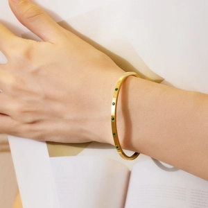 Minimalist 18k gold plated stainless steel bangle featuring five round green crystals