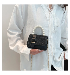 Detailed shot of black sequin handbag with luxury pearl handle and gold buckle detail