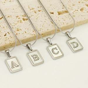 Colliers alphabet en acier argenté avec incrustation de nacre sur socle en pierre