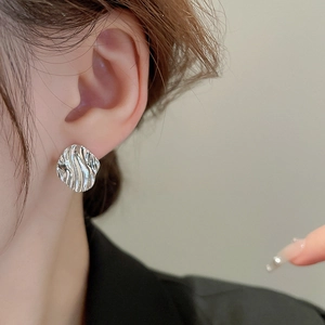 Minimalist silver water ripple irregular stud earrings shown on a female model's ear