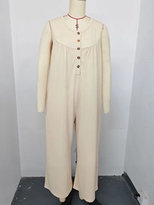 Detail of beige ribbed jumpsuit featuring a buttoned neckline and sleeveless cut
