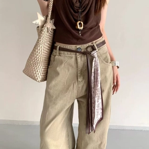 Close-up of khaki wide-leg trousers with brown slim belt and patterned silk scarf detail