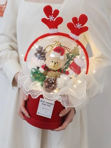 Détail du coffret cadeau de Noël avec ours en peluche, cônes de pin et lumières LED tenu