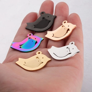 Macro shot of bird-shaped stainless steel pendants in five colors on a palm for size