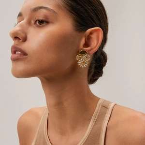 Detail view of 18k gold stainless steel daisy stud earrings worn on a model's ear