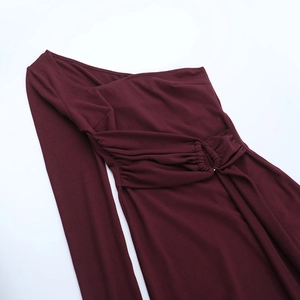 Detail of burgundy one-shoulder dress with metal ring and waist pleats on white background