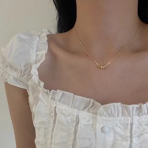 Dettaglio della collana minimalista con perline dorate indossata per un design elegante