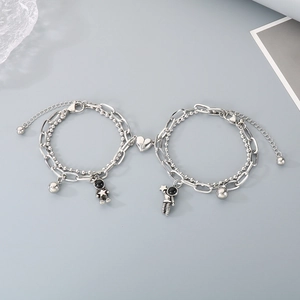 Detail of magnetic heart clasp on double-layered silver astronaut couple bracelets