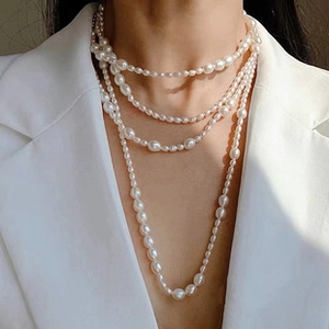 Close-up of layered baroque freshwater pearl necklace on a model wearing white suit