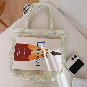 Top view of a floral quilted tote bag on a white table with natural window light shadows