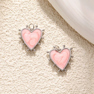 Detailed view of pink heart-shaped enamel charms with silver beaded metal edges