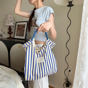 Detail of yellow and blue striped tote with woven handles and brand label in home setting