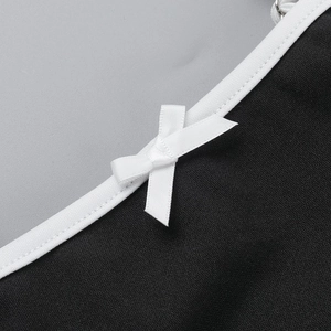 Detail von weißer Satinschleife und Paspelierung auf schwarzem Minikleid mit feinem Stoff