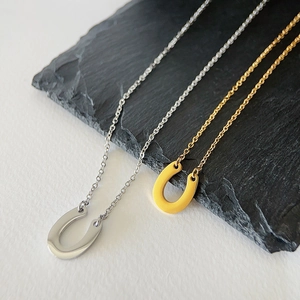 Close-up of horseshoe pendants in gold and silver finish on a dark stone plate