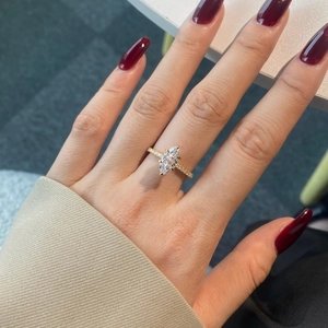 Macro shot of a marquise cut moissanite ring with a gold band and pavé diamonds