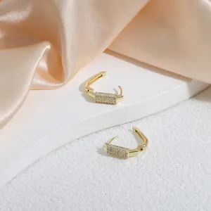 Luxurious gold U-shaped hoop earrings with pave white zircon on champagne silk fabric