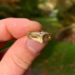 Vintage gold masquerade mask ring with matte texture and sparkling crystals on hand