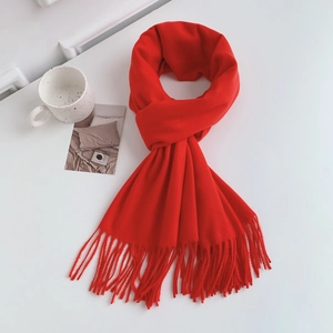 Close-up of soft red cashmere-feel scarf with delicate tassel details and rich texture