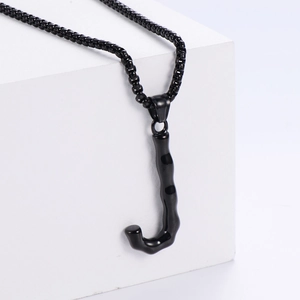 Détail macro du pendentif noir lettre J en 3D avec texture bambou sur une chaîne