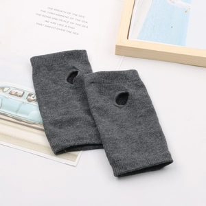 Gants en tricot gris foncé sans doigts avec trou pour le pouce sur bureau épuré