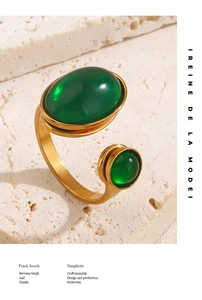 Close-up of golden minimalist ring with two green oval gemstones on natural stone