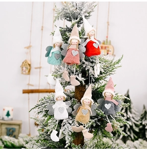 Macro detail of plush angel tree ornaments with sequin hearts on a snowy Christmas tree