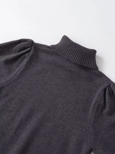 Détail d'un pull en maille gris foncé avec col montant et épaule bouffante à plis fins